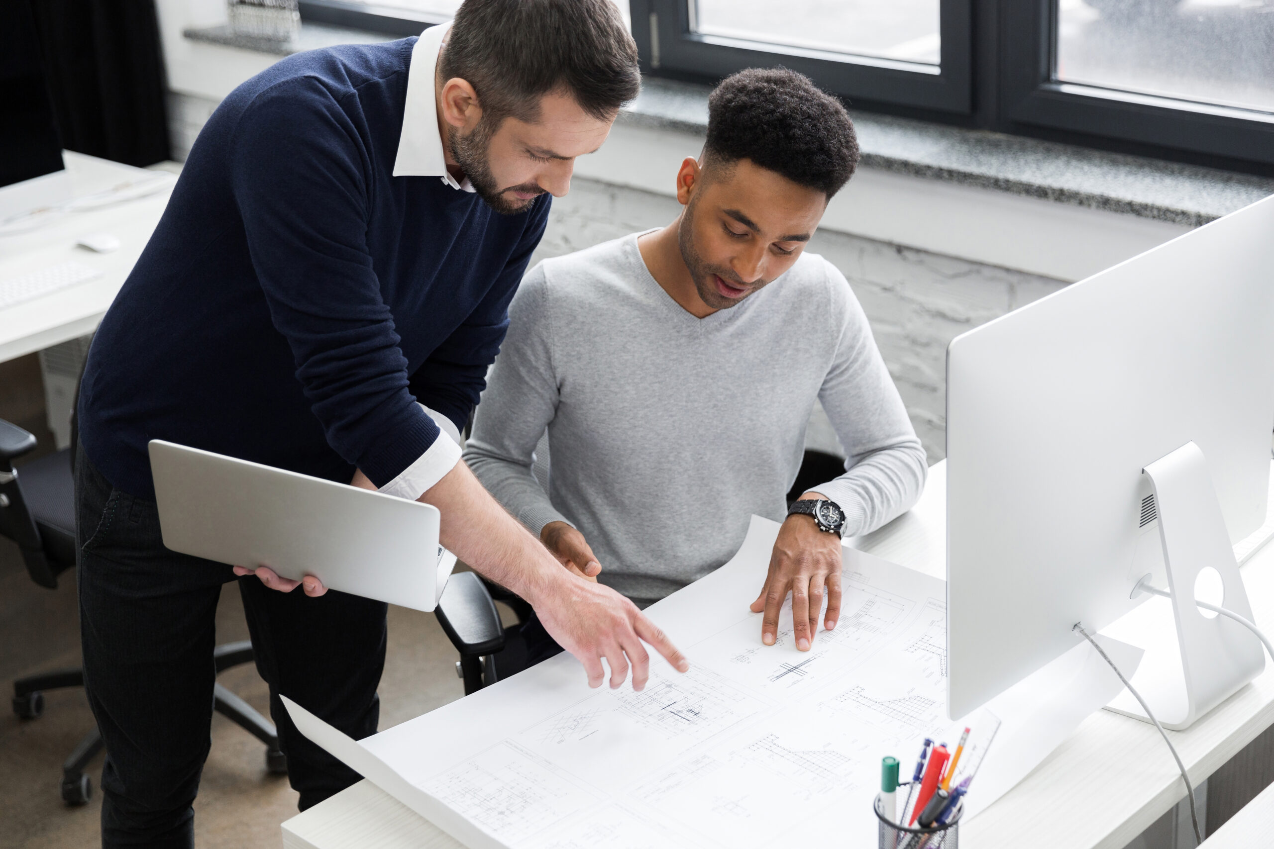 Two smiling male office workers working with laptop SketchUp Pro